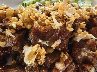 Close-up of savory fried pork with crispy garlic flakes.