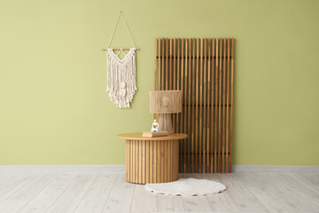 Stylish coffee table with rug, lamp and decor near light green wall