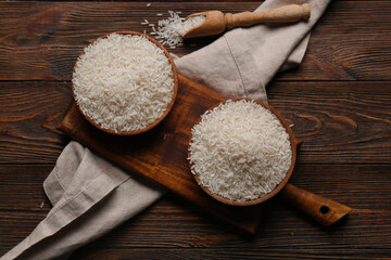 Bowls and scoop with raw rice on wooden background