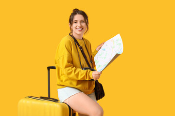 Female traveler with map and suitcase on yellow background. Itinerary concept