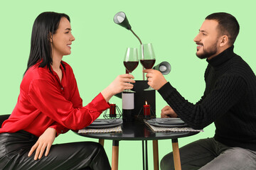Young couple with wine at restaurant table on green background