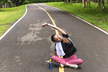 Asian sportswoman sitting and warm up doing exercise in nature park