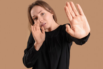 Young woman having panic attack on beige background, closeup