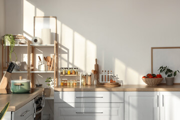 Jars with different spices, food and utensils on counters in light kitchen