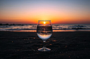 Refreshing glass of water against sunset beach view