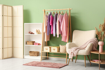 Interior of dressing room with clothes rack, armchair and shelf unit