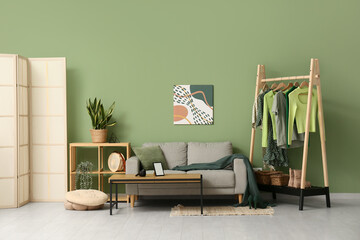 Interior of living room with clothes rack, shelf unit and sofa