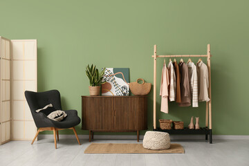 Interior of dressing room with clothes rack, commode and armchair