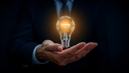 Glowing lightbulb represents innovation in businessman's hand