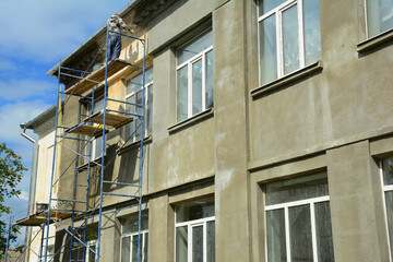 Renovation of the exterior wall of the house using plaster and preparing the wall for painting. Builder applying plaster to the exterior wall of a house.
