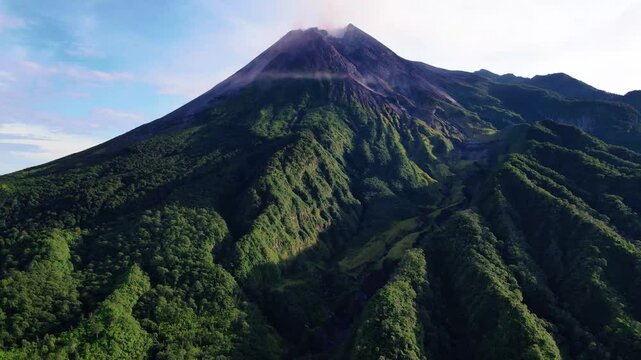 Scenic morning view of Mount Merapi, an active volcano in Central Java, Indonesia. showing volcanic ridges, tropical forest, and atmospheric sunrise light