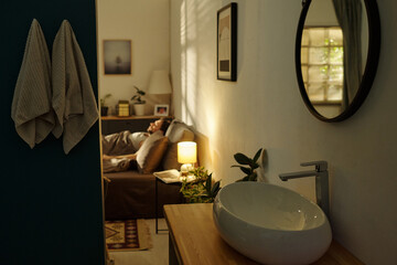 Caucasian man lying in bed appearing stressed with hand on forehead in softly lit bedroom, visible...