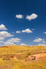 Traditional windmills standing on a hill in Alcazar de San Juan, Spain, under a blue sky