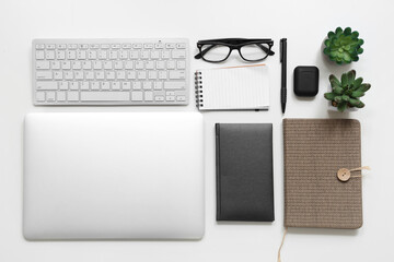 Modern gadgets with eyeglasses, notebooks and plants on white background