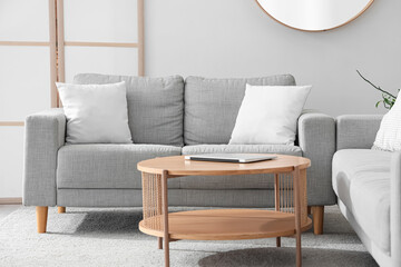 Interior of light living room with grey sofas and table