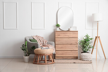Interior of living room with armchair, mirror and commode