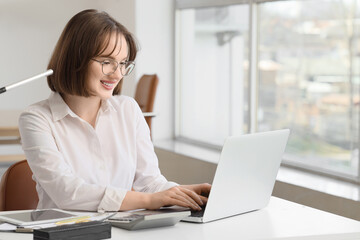Young businesswoman working with laptop at table in office. Cryptocurrency concept