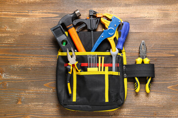 Bag with construction tools on wooden background