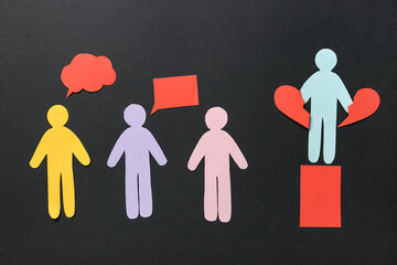 Paper human figures on black background. Concept of oppression