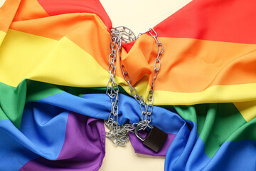 LGBT flag with padlock and chains on beige background. Concept of oppression