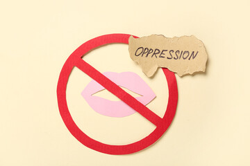 Paper forbidden sign with lips and word OPPRESSION on beige background