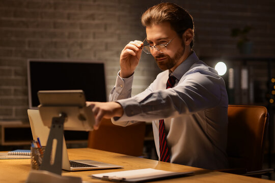 Handsome businessman working with tablet computer in office at night