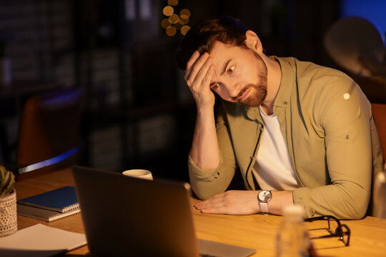 Tired young man working in office at night