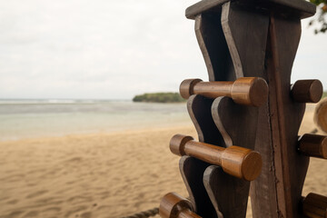 Small wooden dumbbells on a handmade rack by the beach. A peaceful tropical setting promoting...