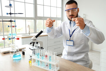 Male scientist with test tubes and microscope working in laboratory