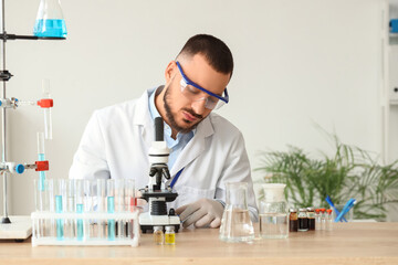 Male scientist with microscope working in laboratory