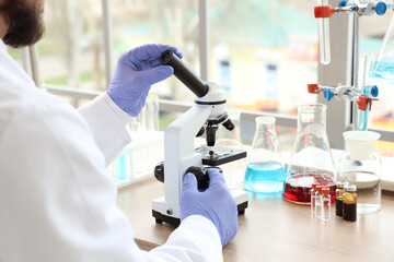 Male scientist with microscope working in laboratory, closeup