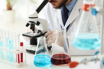 Male scientist looking through microscope in laboratory, closeup