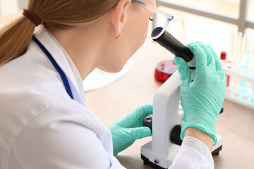 Female scientist looking through microscope in laboratory, closeup
