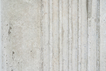 Textured Concrete Surface with Vertical Grooves. A detailed shot of a light grey concrete wall featuring a series of parallel vertical grooves.
