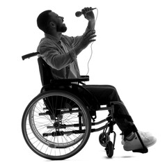 Silhouette of young man in wheelchair with microphone singing on white background