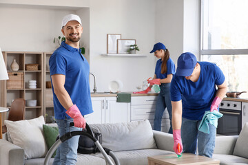 Obraz premium Male janitor using vacuum cleaner in room