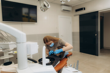Dentist wearing mask and gloves examining patient teeth in dental clinic