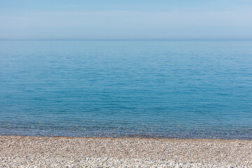 The ocean is calm and clear, with a few rocks on the shore