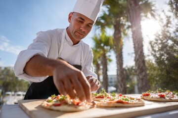 Chef finishing gourmet pizzas with herbs outdoors