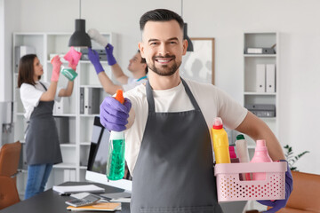 Male janitor with cleaning supplies in office
