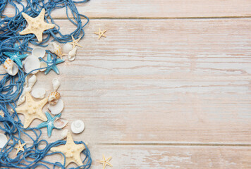 Fishing net, starfishes and seashells lying on wooden planks background