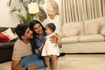 Indian young couple with one infant child sitting on home. Concept of Indian Happy Family Lifestyle