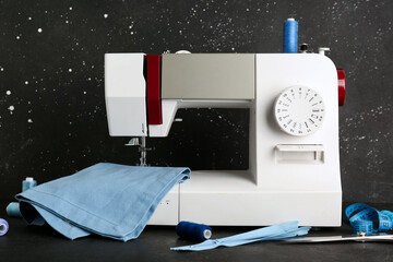 Sewing machine with cloth and thread spools on black table