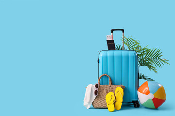 Packed suitcase with beach accessories on blue background