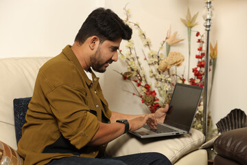Indian young man working on laptop at home