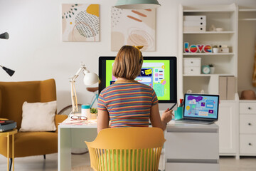 Female web designer working at table in office, back view