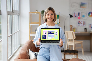 Beautiful female web designer with laptop in office