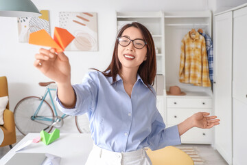 Young Asian businesswoman with paper plane at home