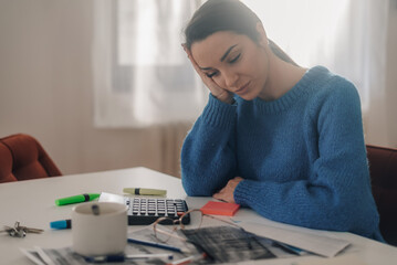 Stressed accountant holding head after calculating taxes at home office desk