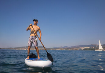 young men  riding  on sup surfing in the sea at sunset